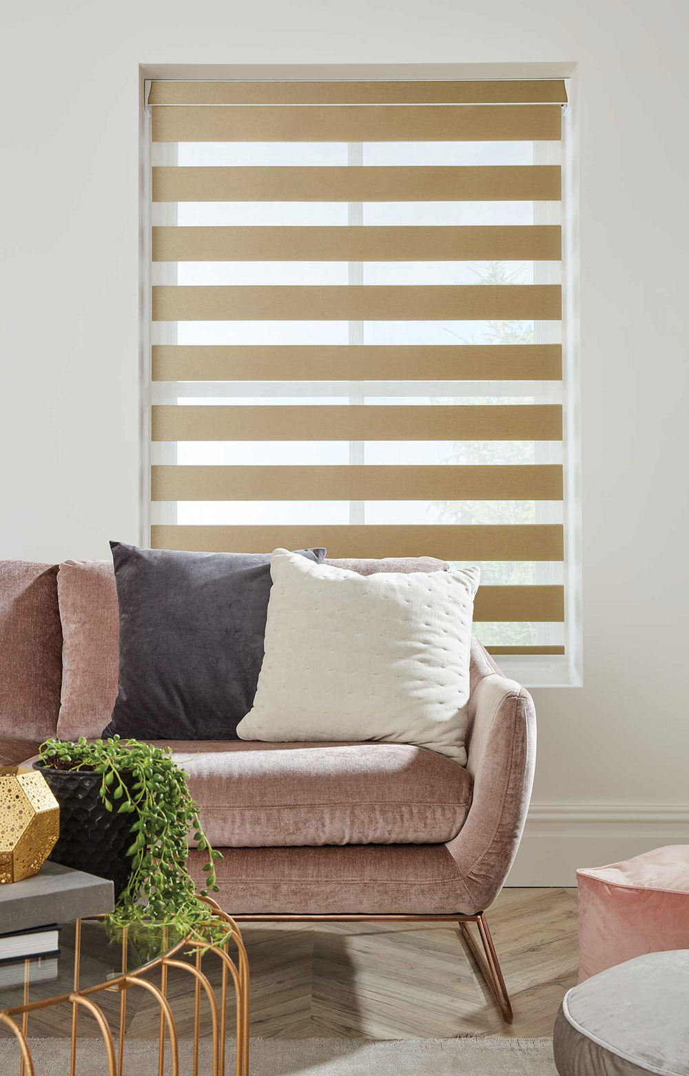 Beige Duo Vision blinds in a living area shown on a tall window beehind a sofa.