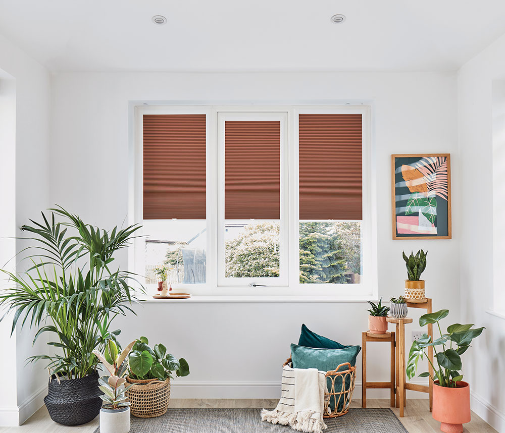 Perfect fit pleated blinds shown in an orange blackout fabric partially closed - 3 windows side by side.